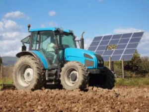 untrattore davanti a dei pannelli fotovoltaici in un campo agricolo